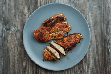 two well-done chicken breasts on a gray plate. one cut into several small pieces
