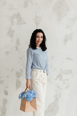 Fototapeta premium brunette girl in a blue sweater holds a bag with flowers