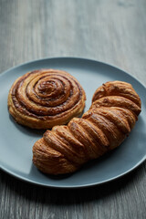 two delicious puff pastry buns on a gray plate on a wooden table.