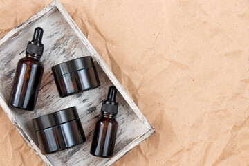 Cometic bottles made of amber glass on crumpled craft paper. Skin care products packaging design....