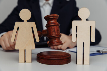 Lawyer or counselor holds gavel behind of figures of young family, divorce and law concept