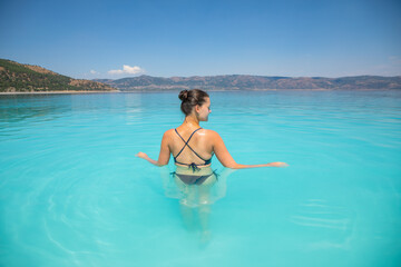 A young sexy female in swim suit is swimming in turquoise crater lake Salda Golu, Turkey