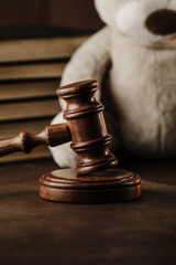 Divorce and separation concept. Wooden gavel close-up and teddy bear as symbol of child. Vertical...