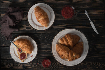 Croissants with rasberry jam on brown wooden table. Flat lay.