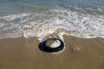 Used car tyre on the sea beach.