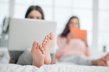 Legs of girl sitting with laptop on bed