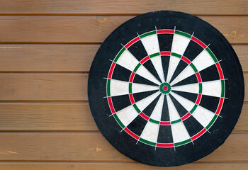 Darts board on brown wooden background.