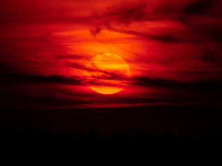 evening sunset sky with sun and clouds in red tones