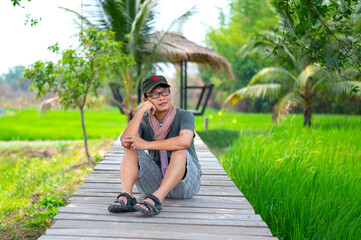 Handsome Korean man sits on a wooden bridge thinking about his girlfriend.Asian people concept.