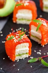 Mini sandwiches with smoked (salted) salmon or trout, avocado, cream cheese, sesame seeds and micro-greens on white bread. A delicious snack. Canapes. Tapas. Breakfast. Selective Focus