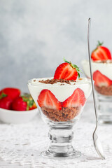 Layered Dessert of chocolate sponge cake, whipped cream or ricotta and fresh strawberries in a glass bowl. Trifle.  Delicious gourmet breakfast. Selective Focus, copy space