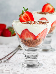 Layered Dessert of chocolate sponge cake, whipped cream or ricotta and fresh strawberries in a glass bowl. Trifle.  Delicious gourmet breakfast. Selective Focus, copy space