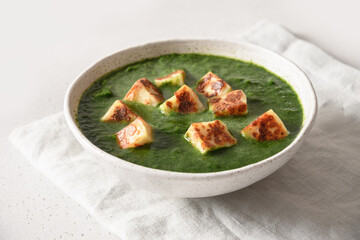 Indian vegetarian cuisine Palak Paneer of spinach and paneer cheese on white background. Close up.