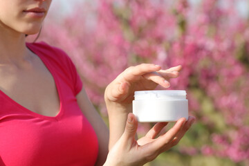 Woman hands in pink holding moisturizer cream outdoors