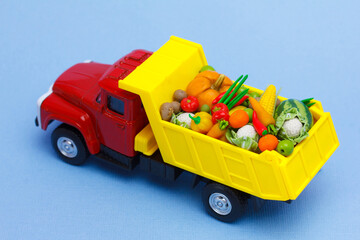 peasant farm vegetables shipping. A  toy truck delivering fresh fruits and vegetables. Isolated on  blue background