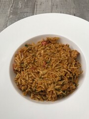 A bowl of chicken tikka biryani against a wooden background