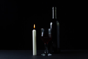 Wine and candle on a dark background. Creative photo of red wine on a black background. Wine by candlelight