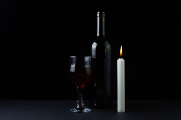 Wine and candle on a dark background. Creative photo of red wine on a black background. Wine by candlelight