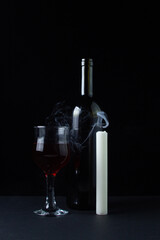 Wine and candle on a dark background. Creative photo of red wine on a black background. Wine and candle smoke