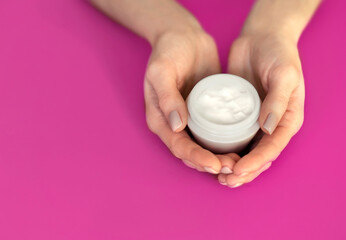Female hands hold a container with hand or face cream