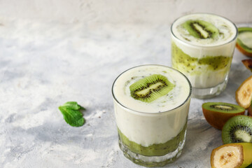 Yogurt with kiwi in a glass. Fruit and berry smoothie. Milkshake with kiwi and banana. Healthy eating. Light background. Copy space.