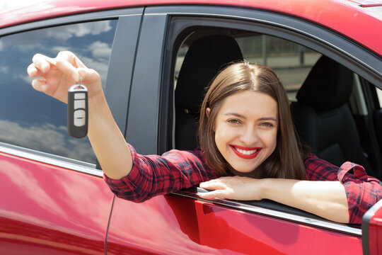 Driver woman smiling showing new car keys and car. Happy woman driver showing car keys and leaning on car door