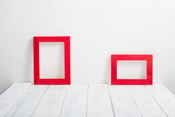 pair of empty red picture frames on white wooden table