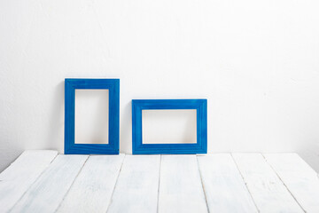 two empty blue picture frames on white wooden table
