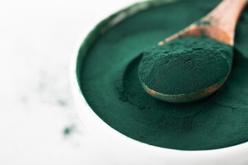 Obraz na płótnie Canvas spirulina powder in a cup and spoon, macro, texture
