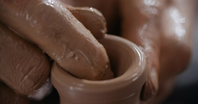 MACRO SHOT: potter sculpts a small ceramic glass in slow motion on a potter's wheel, small forms in pottery, potter makes ceramics in slow motion, 4k 60p Prores HQ 10 bit