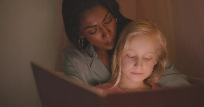 Mother reading her cute little girl a bedtime
story