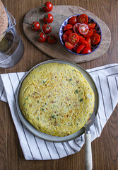 Spanish Omelette dinner from top view. Sliced tortilla on table with a served slice. Side salad made of tomatoes. 