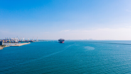 Container ship approaching port city, surrounded by vast blue sea, highlighting logistics, import-export business, and maritime economy. © AU USAnakul