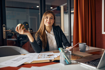 Female architect sitting at the desk with technical drawings