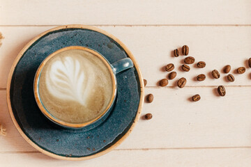 blue cup of coffee with beans on a light wooden background