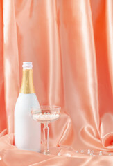 Smooth luxury design made with silk or satin curtain, champagne bottle and crystal glass filled with white pearls. Minimal composition.