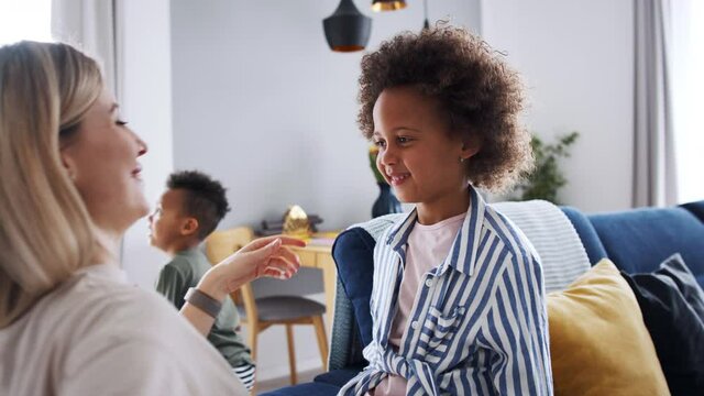 Mother with small daughter getting dressed at home, multi ethnic family.