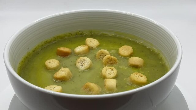 Zucchini cream soup (vellutata di zucchine) and croutons, isolated on white background
