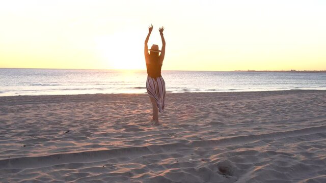 young woman with hat walking on a beach in southern spain