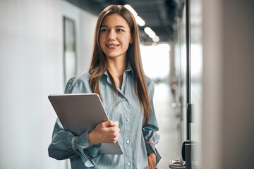 Pleased employee with a laptop standing in the corridor