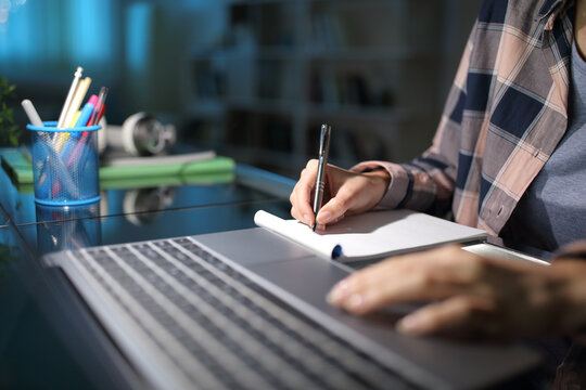 Student Hand Taking Notes Checking Laptop In The Night