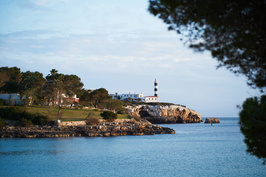 Seascape with a lighthouse in Portocolom, Mallorca taken behind trees