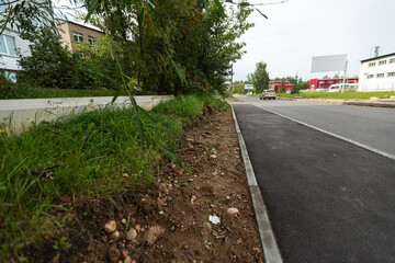 sidewalk and green grass. asphalt pedestrian path along the unkempt lawn