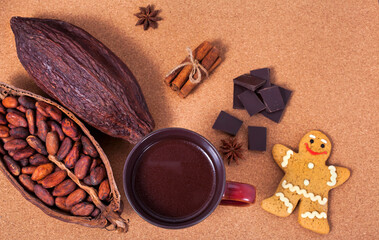 Cup of cacao drink with gingerbread man, chocolate bar, spices, cocoa pod and cocoa beans on a cork...