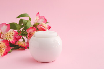 Candle in holder and flowers on color background