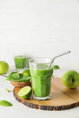 Glass of tasty green smoothie and ingredients on light background