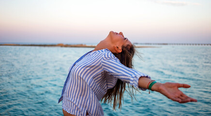 Woman enjoying freedom. Standing arms outstretched back and enjoy life on the beach at sea under...