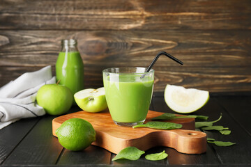 Glass of healthy green smoothie and ingredients on dark wooden background