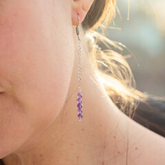 Female ear wearing long amethyst mineral stone earring
