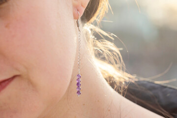 Female ear wearing long amethyst mineral stone earring